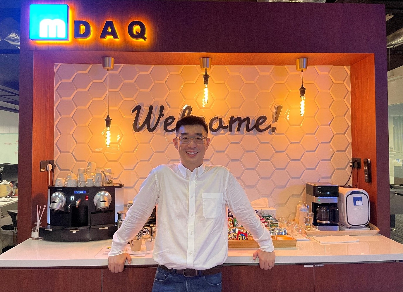 Richard Koh smiling at the coffee counter in the M-DAQ office