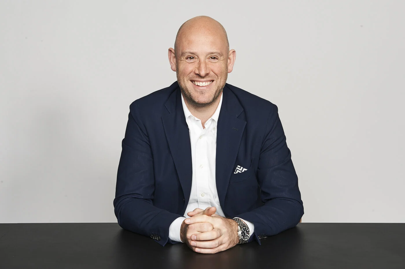 Richard Moross seated at a table, smiling in a navy jacket