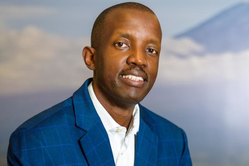Richard Okello in a blue checked jacket, in a press photograph