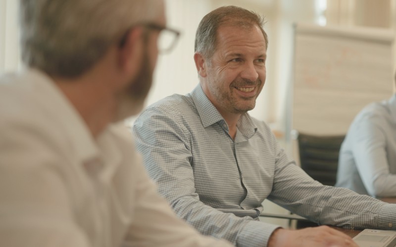 Richard Pennington seated at a table in conversation with colleagues