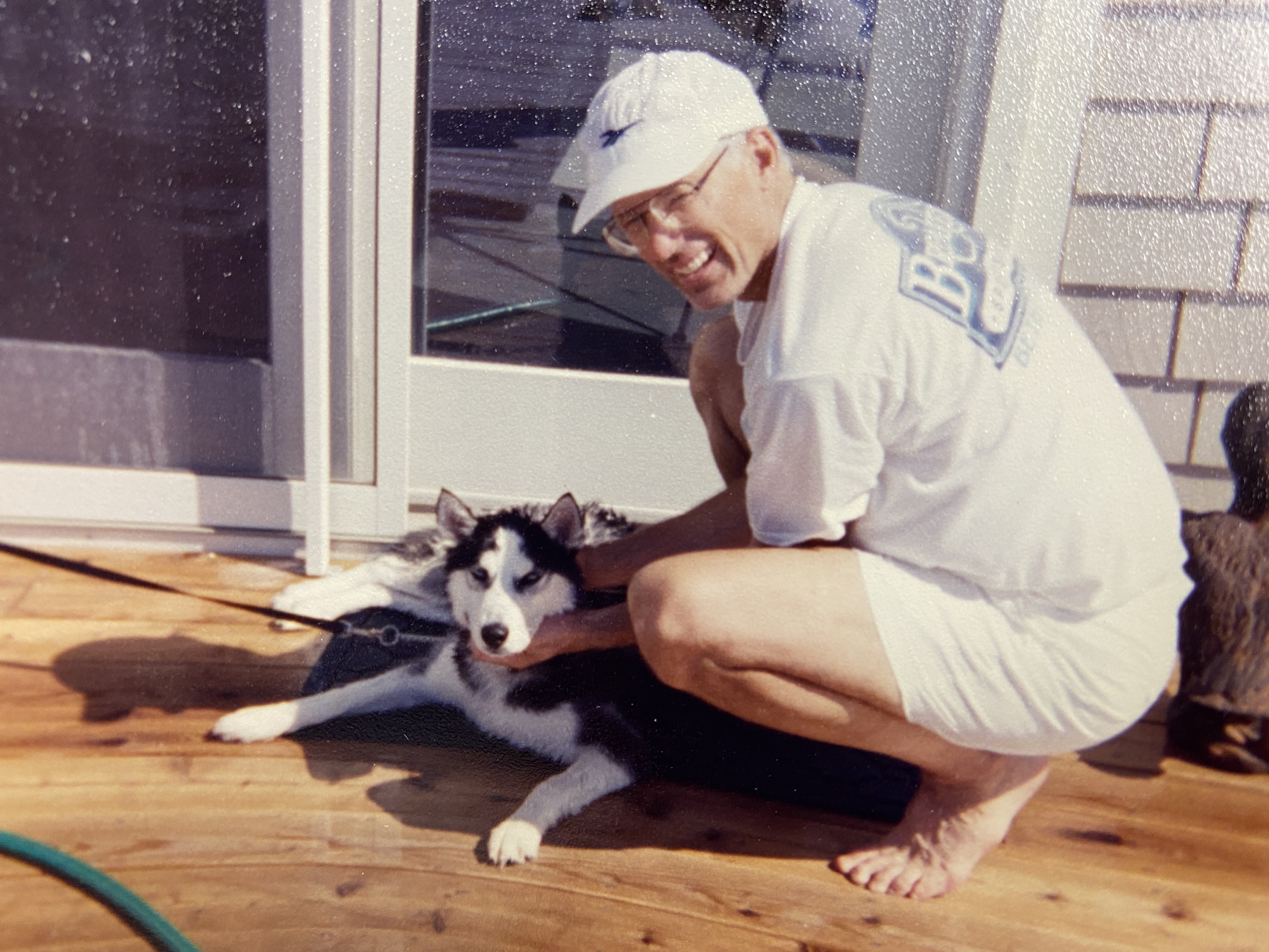 Rick Sharp smiling beside a dog on a wooden deck, in an undated candid photograph.