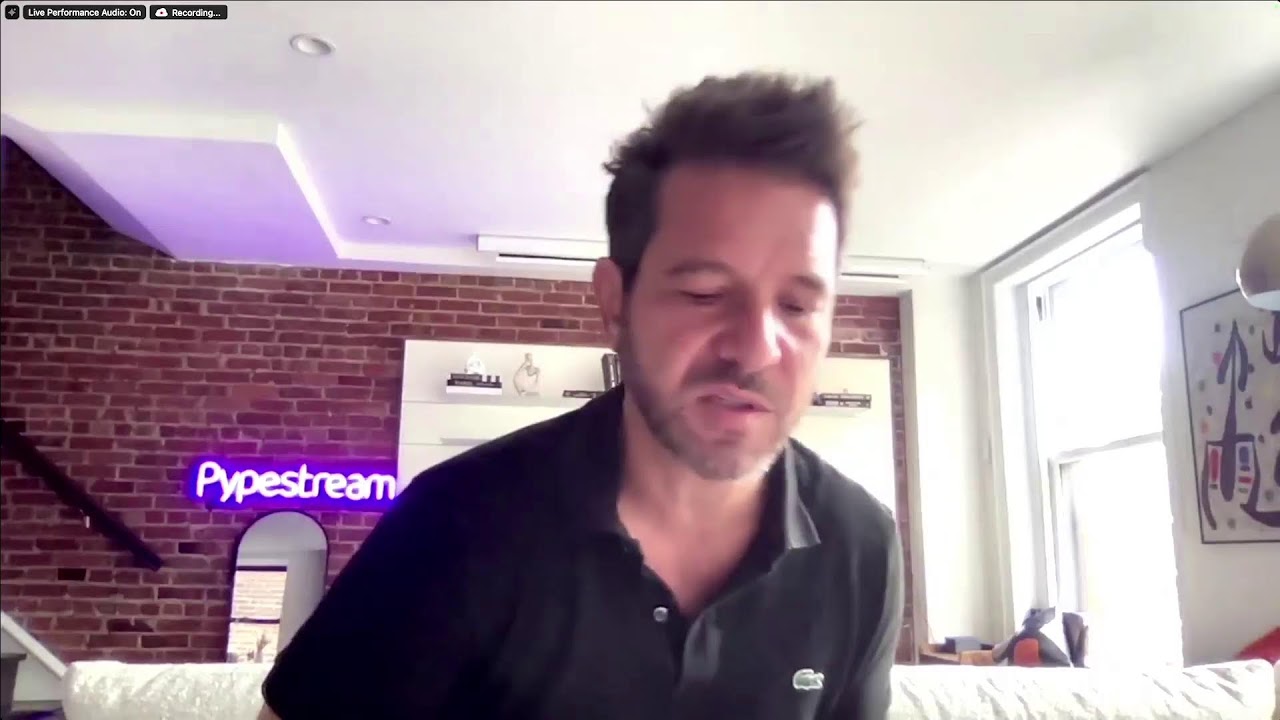 Richard Smullen speaking during his June 2024 VUX video interview, with a Pypestream sign behind him
