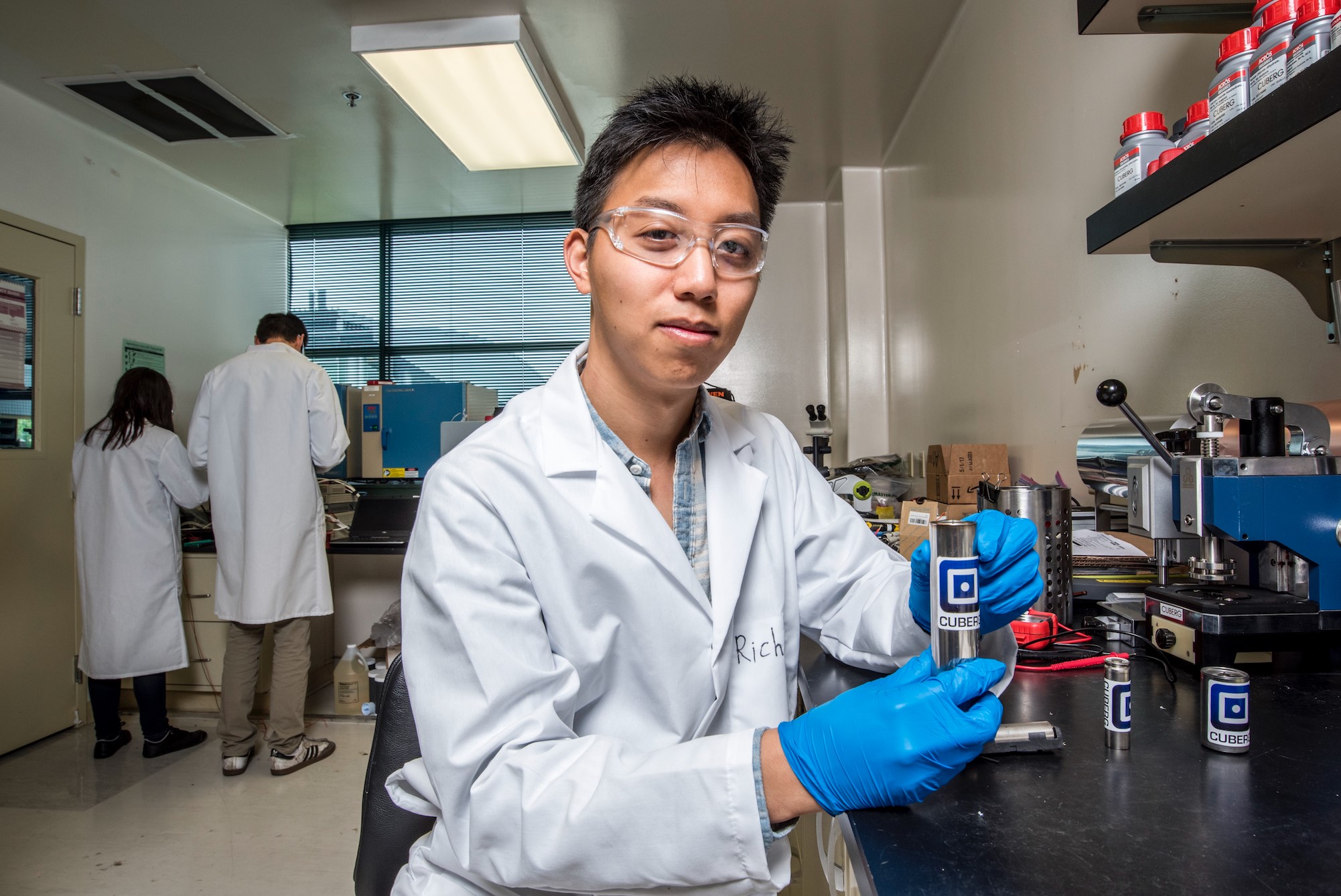 Richard Wang in a Cuberg laboratory, wearing safety glasses and holding a cylindrical cell