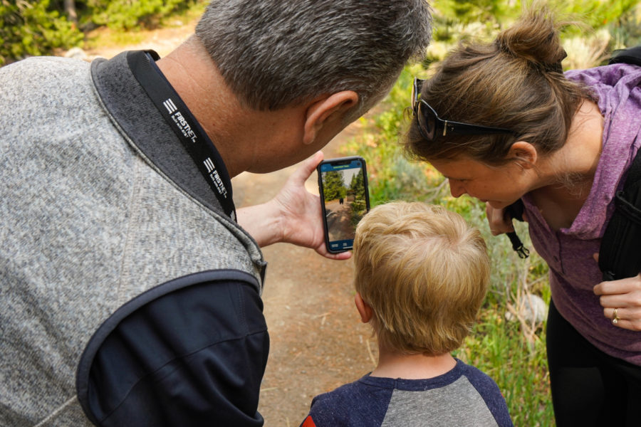 Park visitors look together at a smartphone while standing on a trail