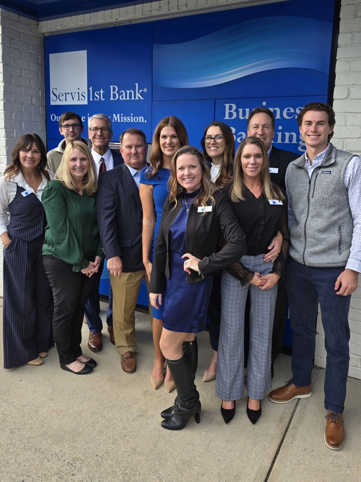 Rick Manley, wearing a navy jacket and tan trousers, with colleagues at the ServisFirst Cornelius office opening