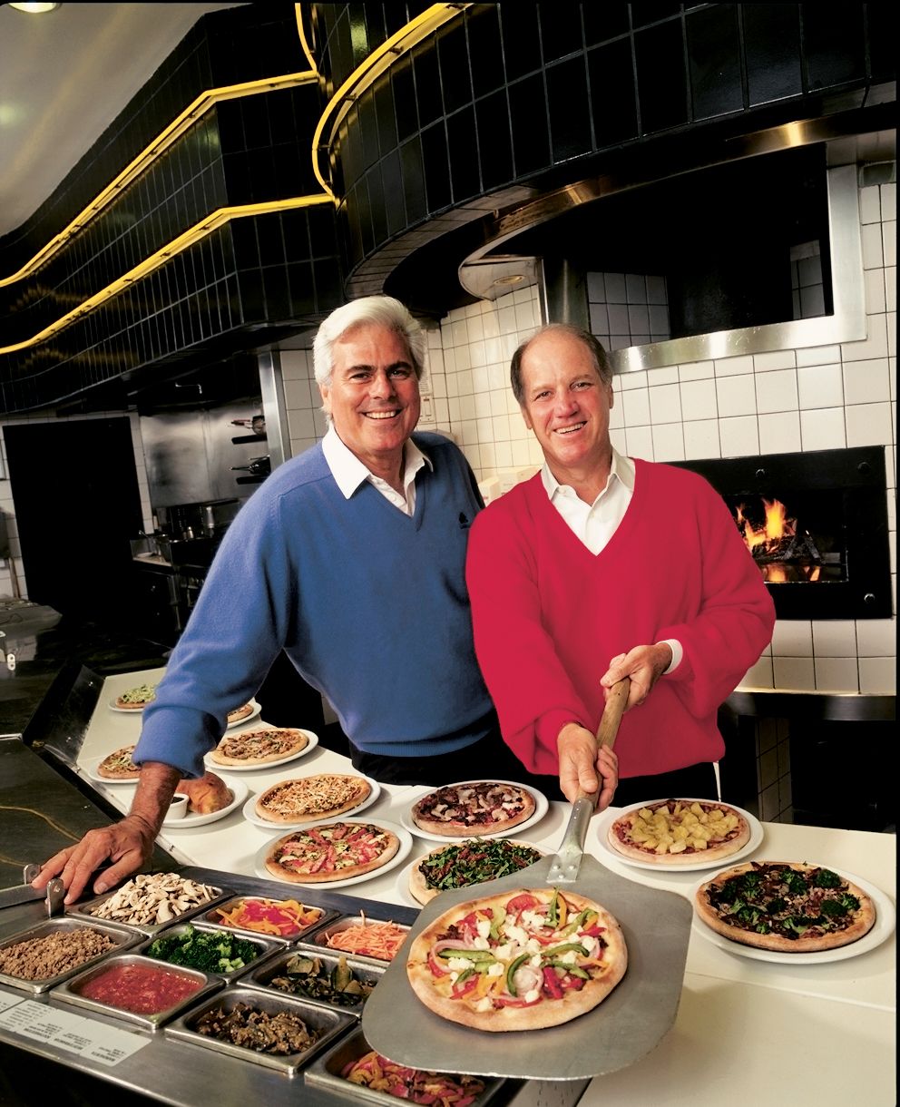 Larry Flax and Rick Rosenfield in a pizza kitchen, with Rosenfield holding a pizza peel