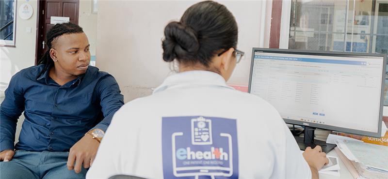 A staff member works at a Cellma screen beside a seated man in the photo accompanying RioMed’s Guyana pilot announcement