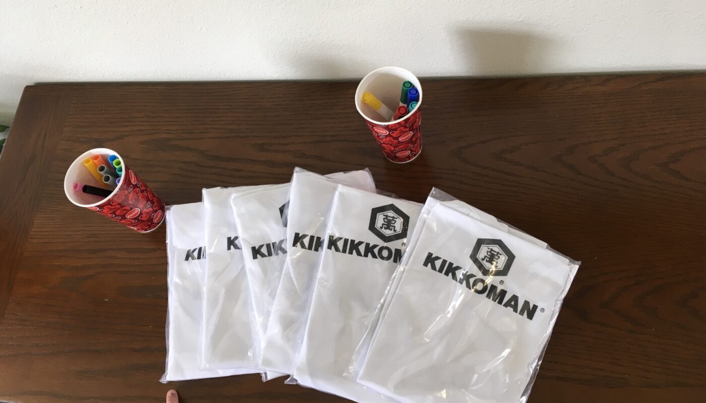 Kikkoman-branded party supplies and cups of colored markers arranged on a wooden table