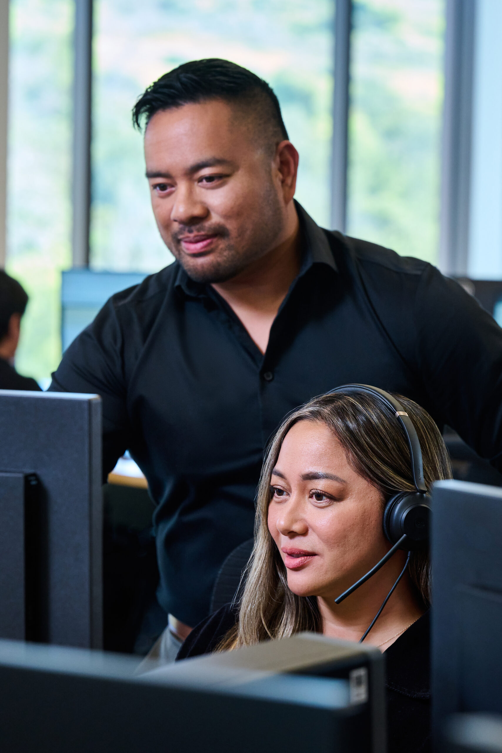 Two RIS Rx colleagues work together at a computer, one wearing a support headset.