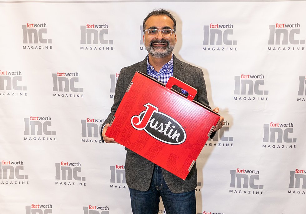 Rishi Khanna smiling while holding a red Justin boot box at the entrepreneurship awards pickup event