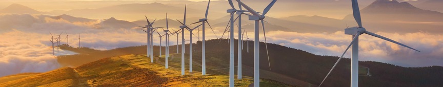 Wind turbines following a mountain ridge above low clouds