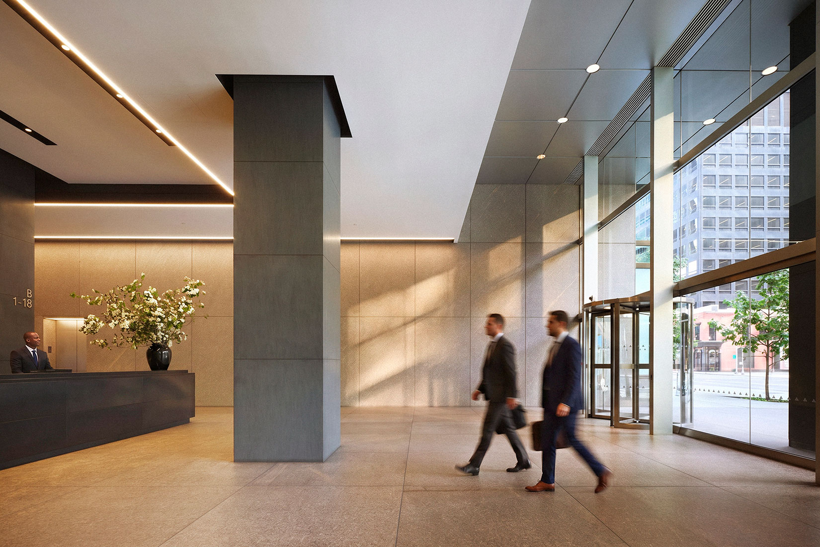 Sunlight enters the lobby of Elecor’s 900 Third Avenue office building as two people walk past the reception desk.