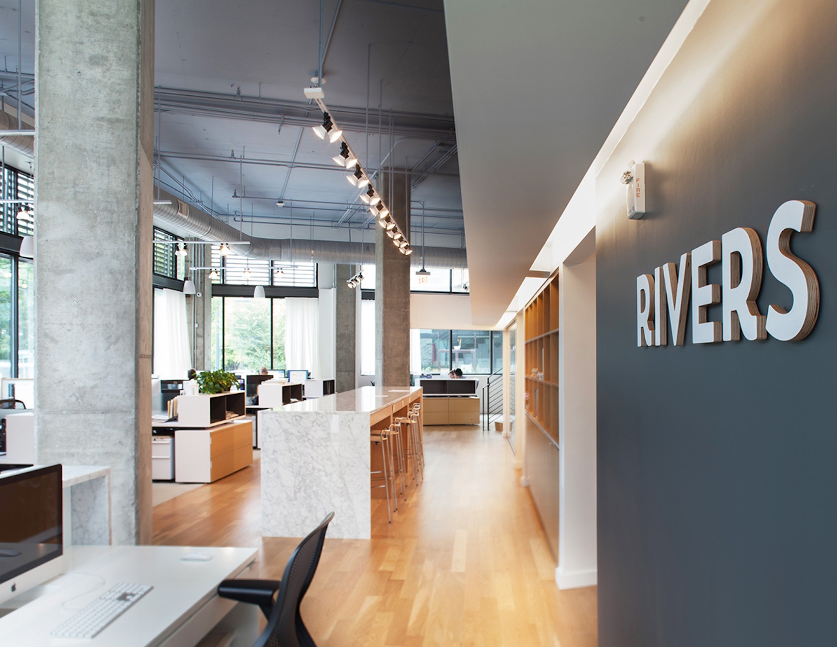 Interior of Rivers Agency's Chapel Hill office showing the Rivers wall sign and open workspace