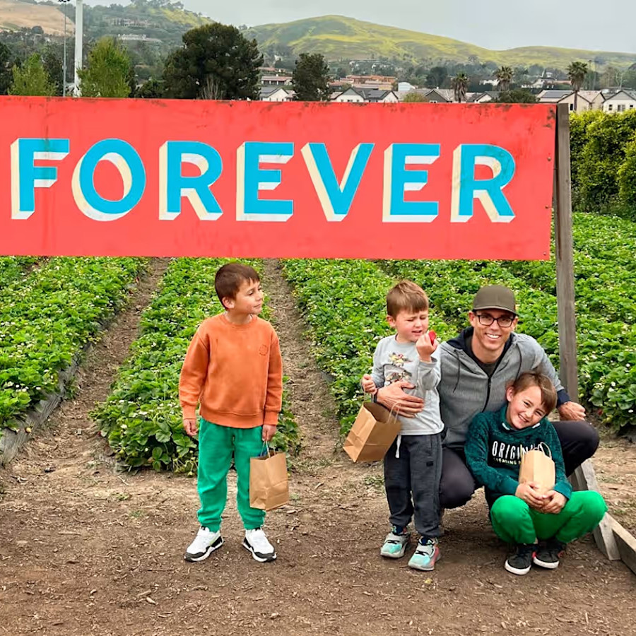 RJ Scaringe with his children outdoors beneath a FOREVER sign