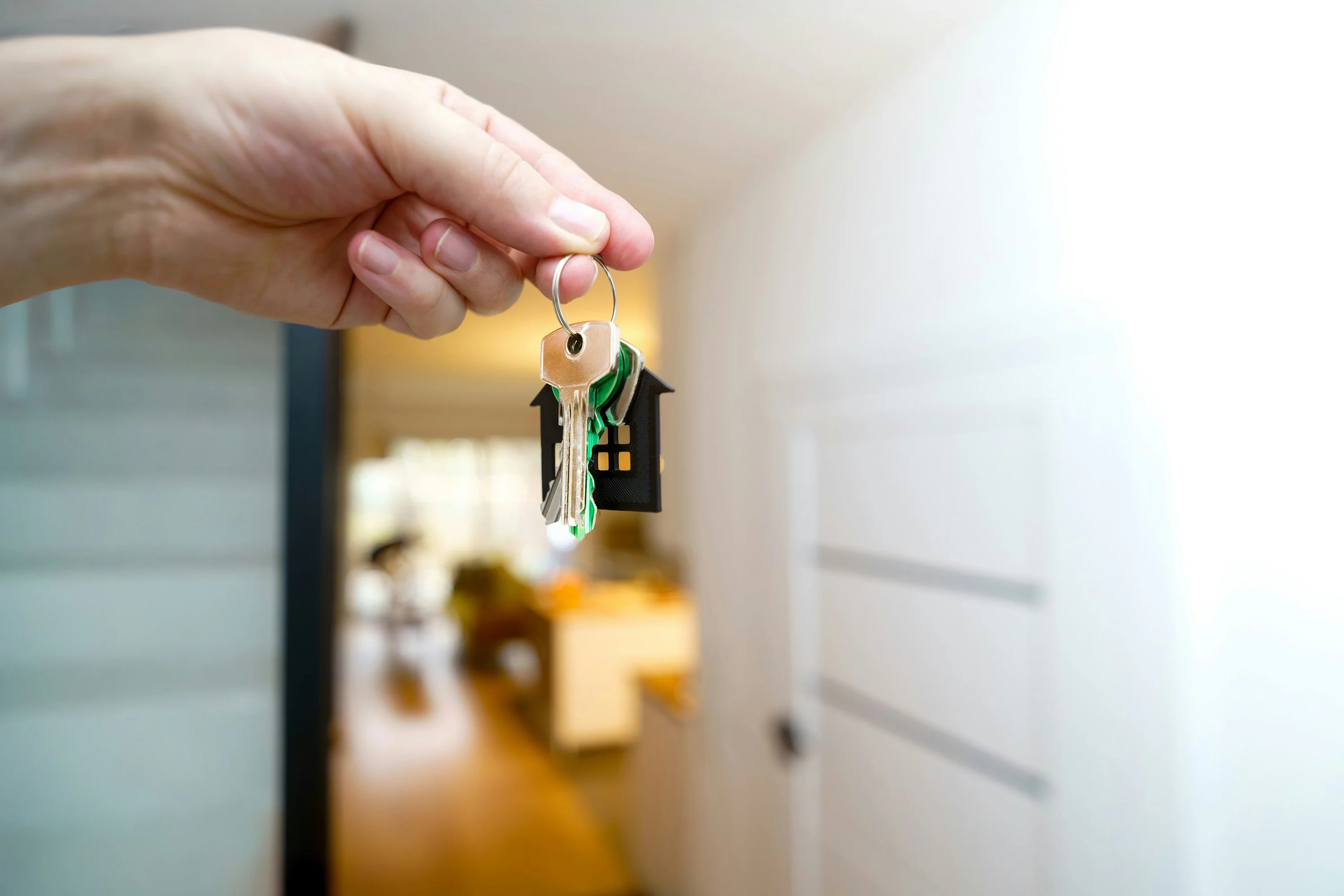 A hand holding house keys beside an open door