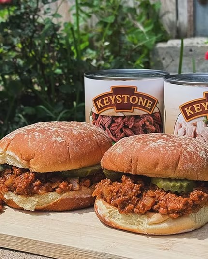 Keystone Meats cans behind two sandwiches