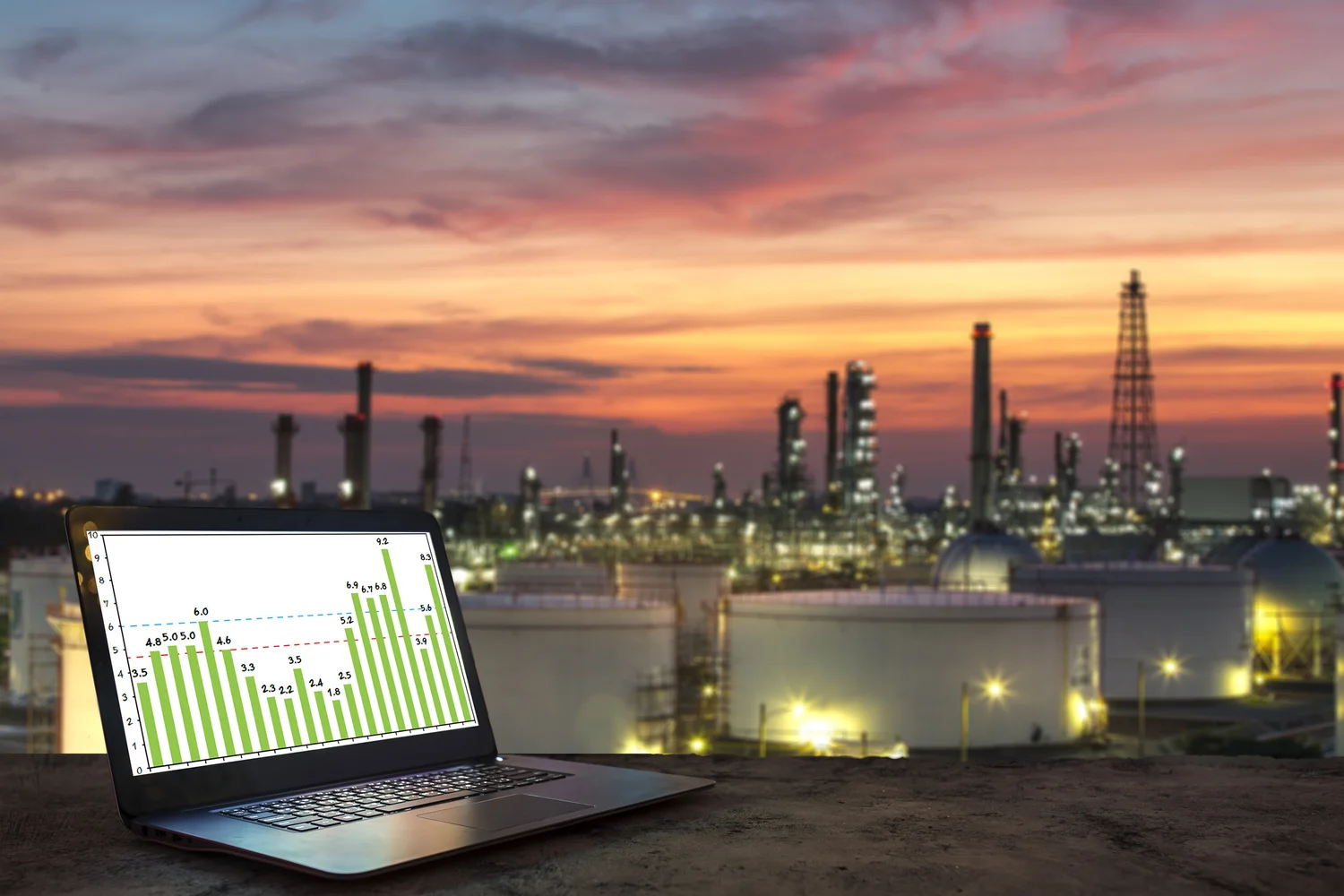 Industrial facility at dusk with environmental monitoring data on a laptop