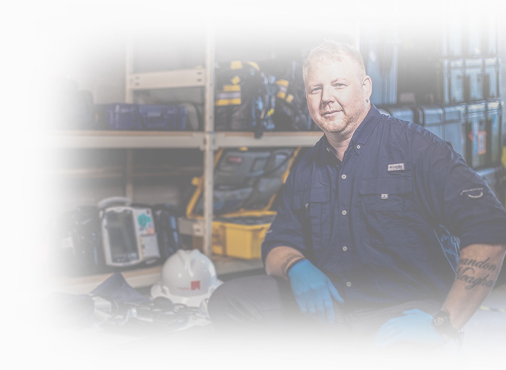 A medical provider in gloves beside equipment cases and a hard hat