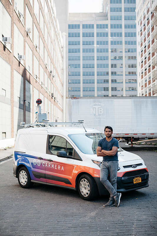 Ro Gupta standing beside a CARMERA mapping van on a city street