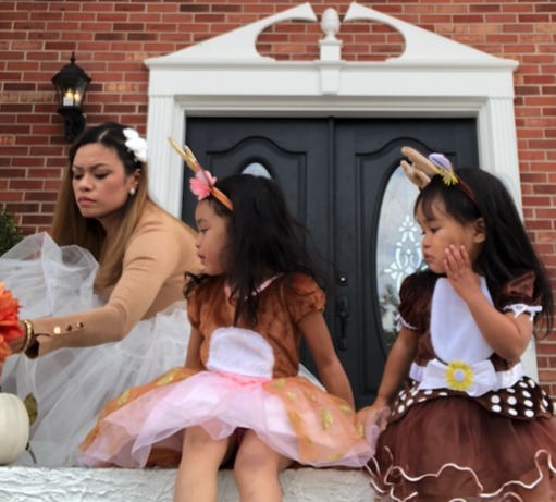 Ro Lujan arranging a seasonal display with her two daughters in costume