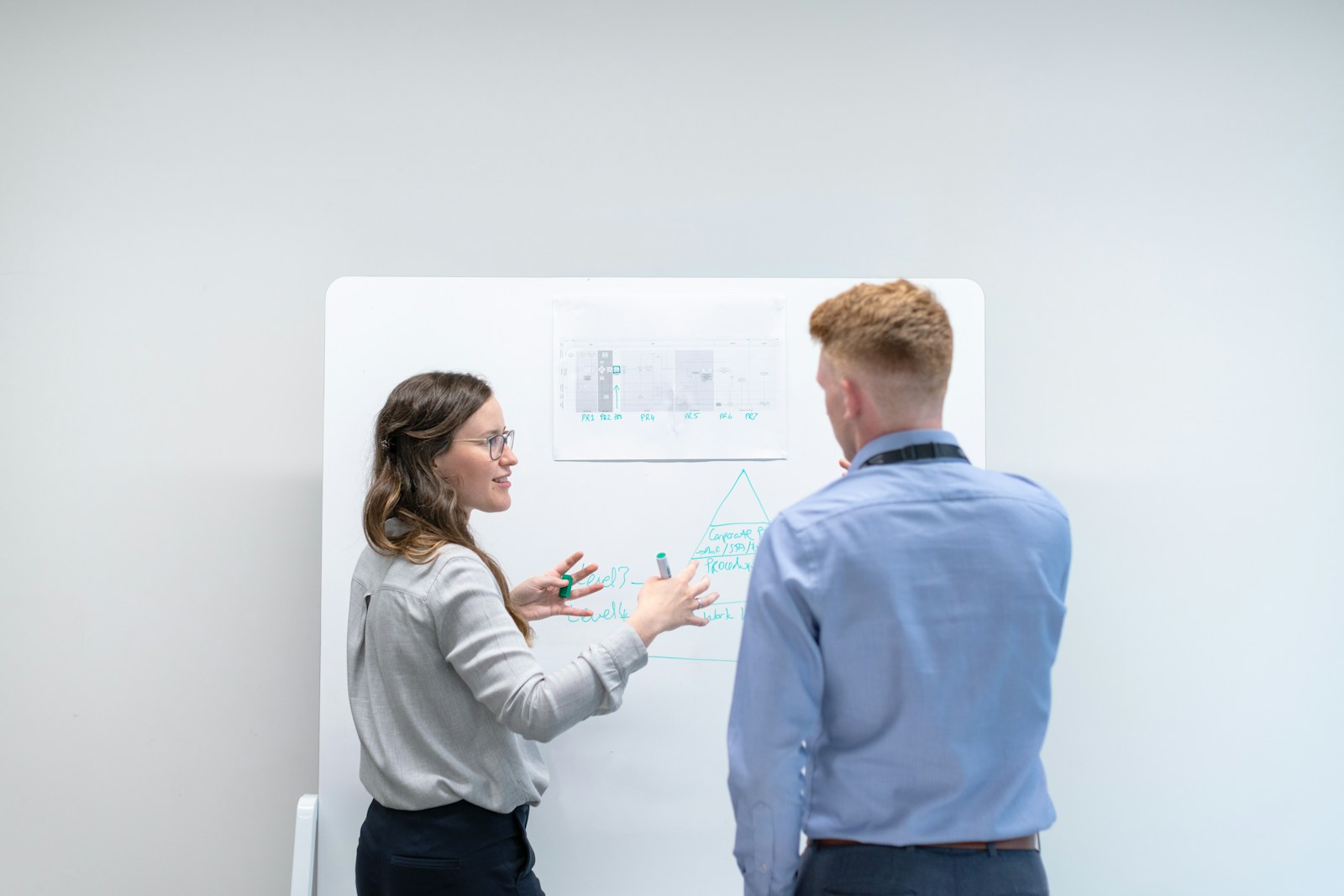 Two colleagues discussing technical ideas at a whiteboard