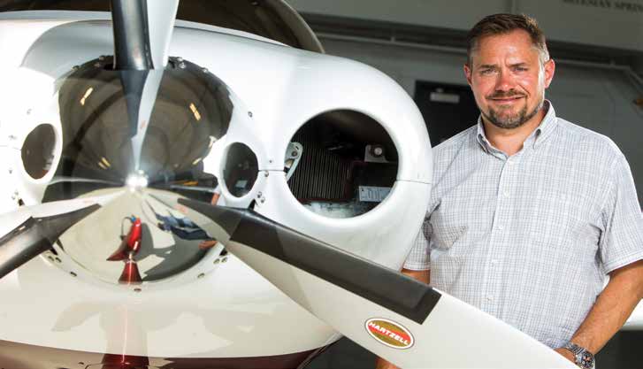 Rob Donat beside the propeller and nose of a small aircraft in a hangar