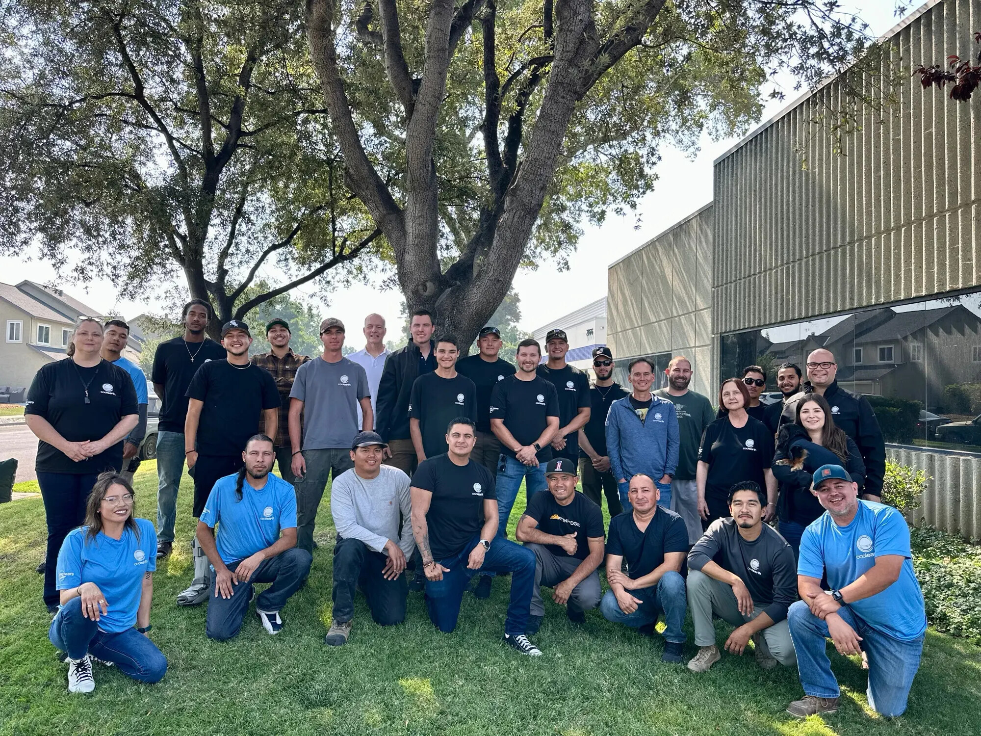 The Cool Earth Solar team gathered outdoors beneath a large tree, with Rob Lamkin standing near the center