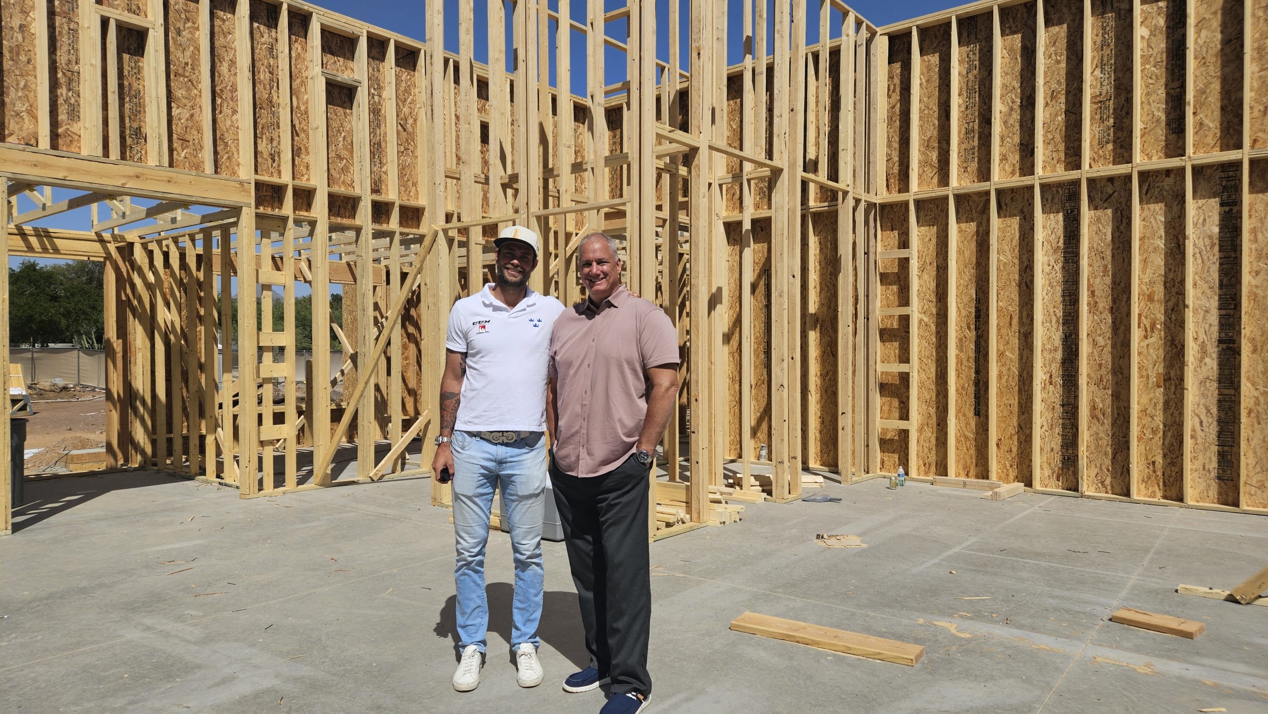 Eddie Lack and Rob Licopoli standing inside the timber frame of a building under construction