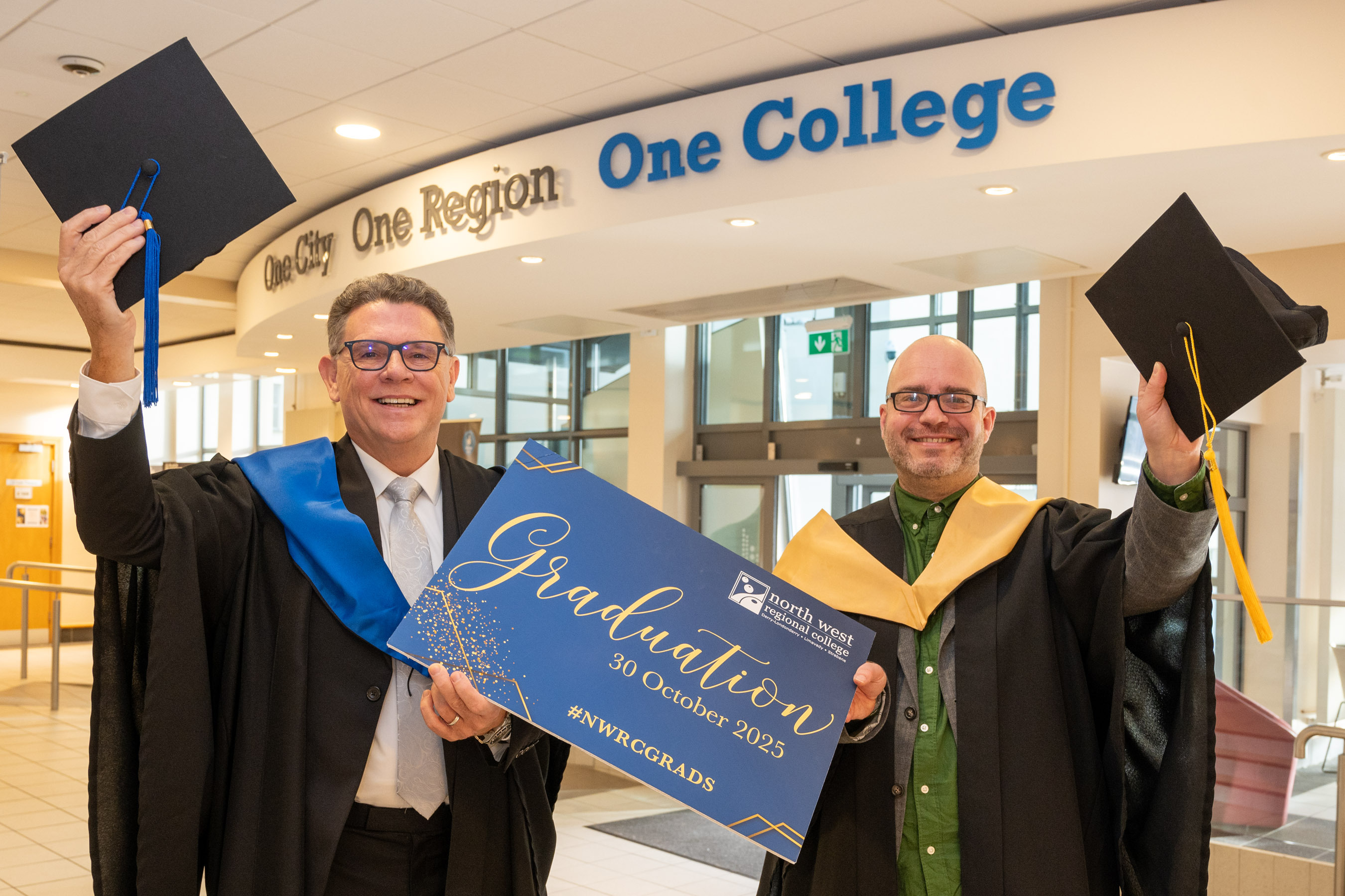 Robert O’Brien, left, and Alastair Cameron in academic robes, raising their mortarboards at North West Regional College