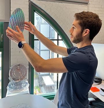 Robert Devlin holding a patterned semiconductor wafer up to the light