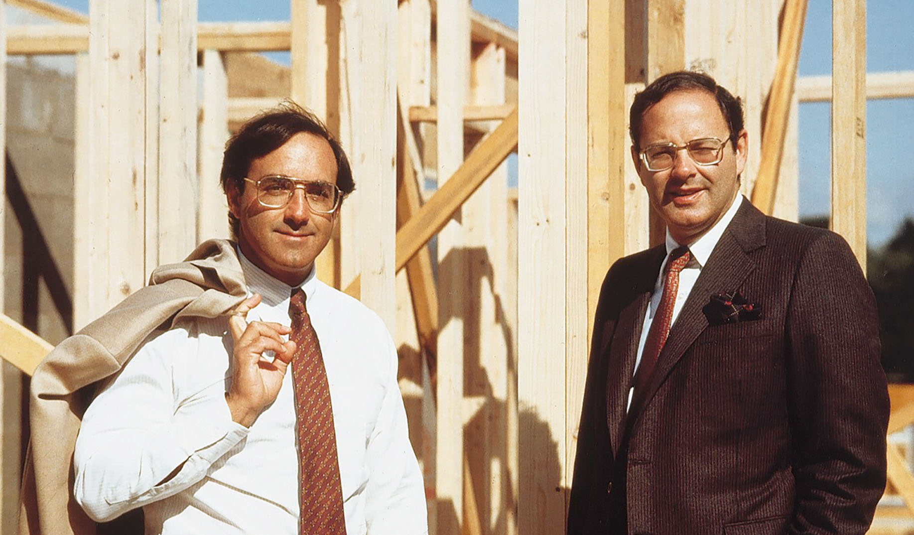 Bob Toll, left, and Bruce Toll standing beside the timber frame of a house