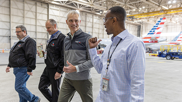 Robert Isom, center, walking through an aircraft hangar with American Airlines employees