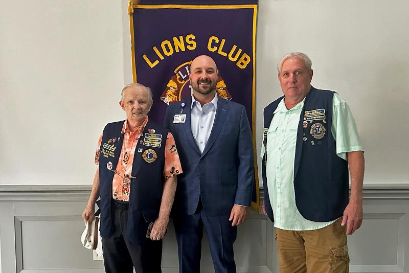 Bob Ervin, Robert Marmerstein and Bubba Hardee standing beneath a Tomball Lions Club banner