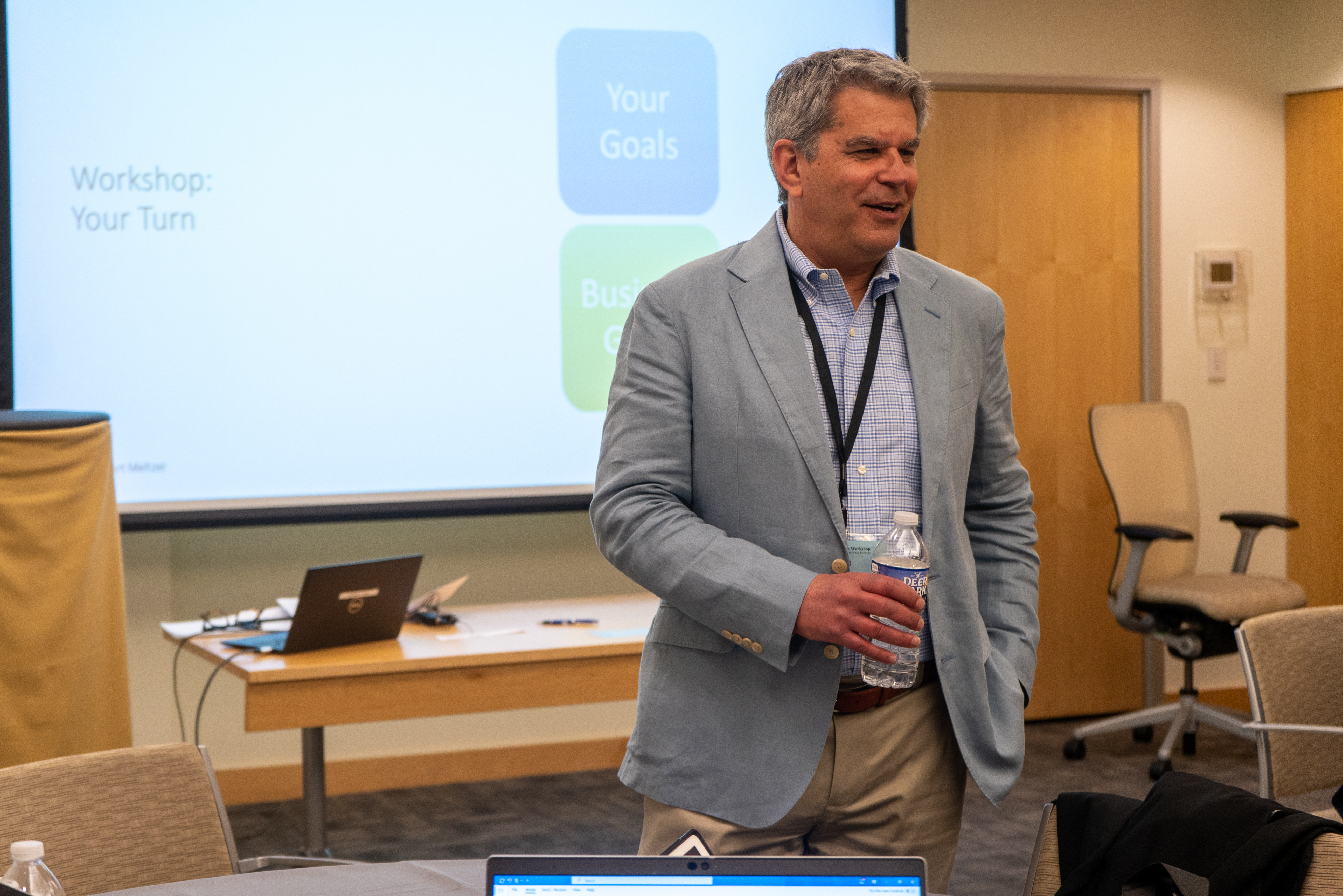 Robert Meltzer standing in a workshop room with a presentation screen behind him