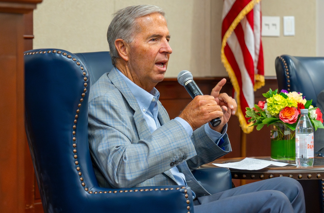 Robert Rowling holding a microphone during a seated conversation at SMU