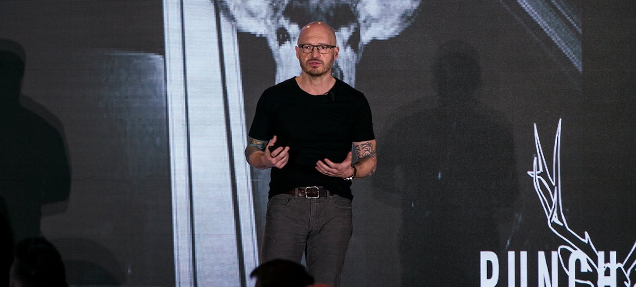 Robert Thompson speaking onstage at RestaurantSpaces, gesturing in front of a Punch Bowl Social presentation