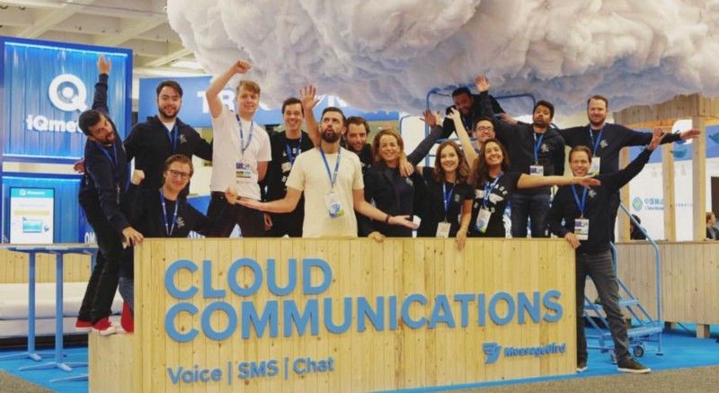MessageBird team gathered behind a wooden Cloud Communications stand