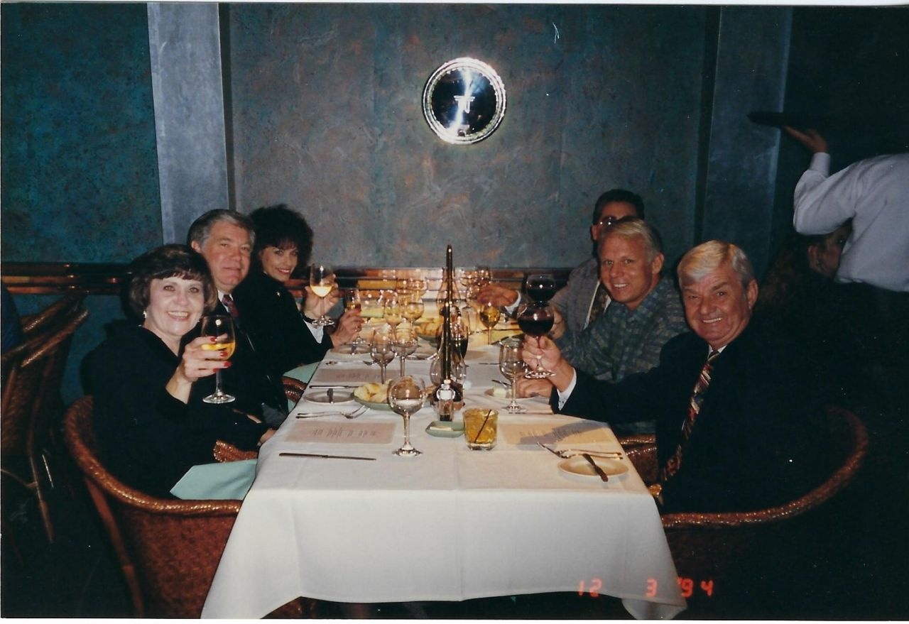 Robert Young and colleagues raising glasses around a restaurant table in an archival company photograph