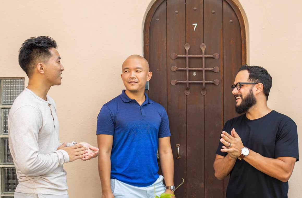 Welcome’s three co-founders talking together outside, with Roberto Ortiz smiling at right
