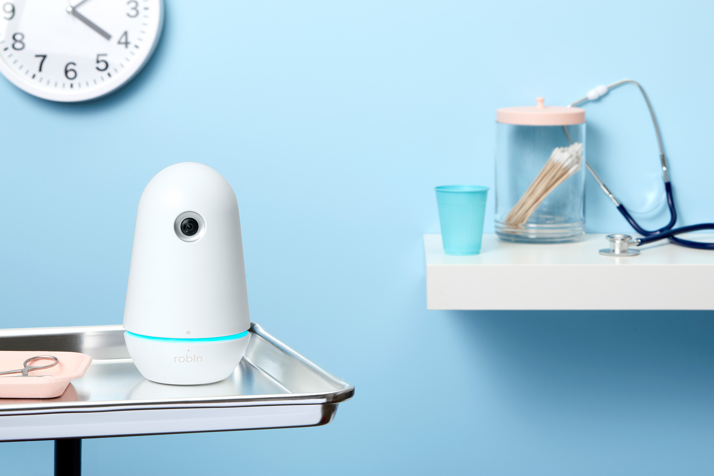 Robin Assistant device standing on a clinical tray in a blue exam room