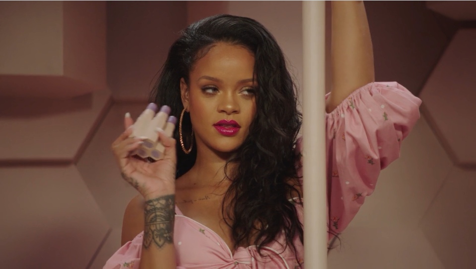 Rihanna holding Fenty Beauty products in a pink outfit during a 2018 campaign