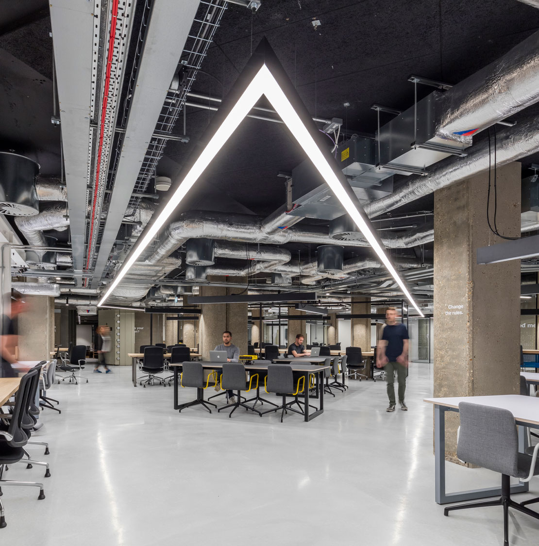 Tables and chairs below a triangular light in RocketSpace’s London campus