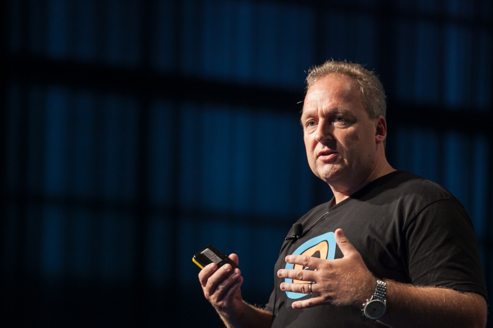 Rod Drury speaking on stage, holding a presentation clicker
