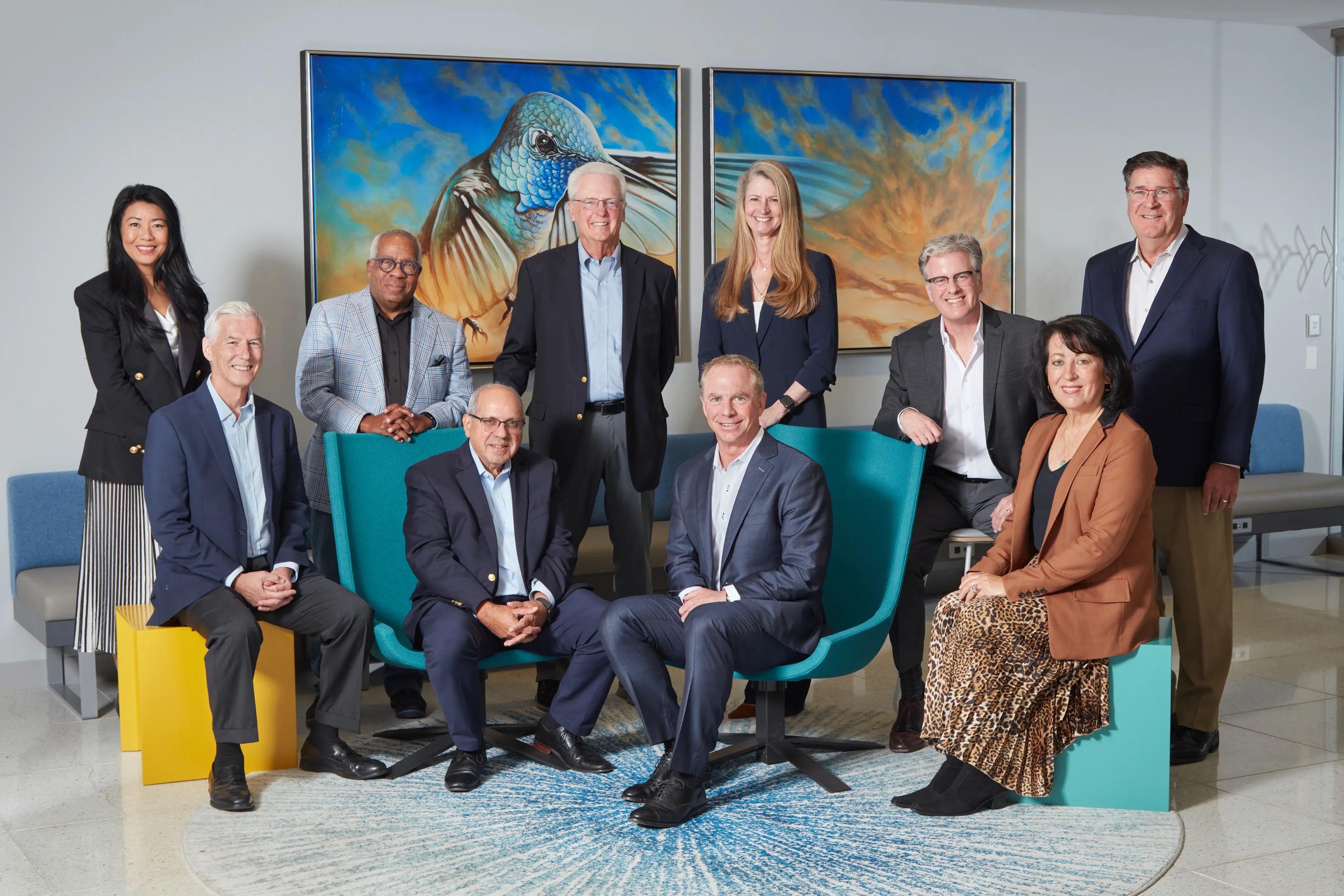 Rod Little seated with fellow Edgewell board members in front of two colorful hummingbird paintings