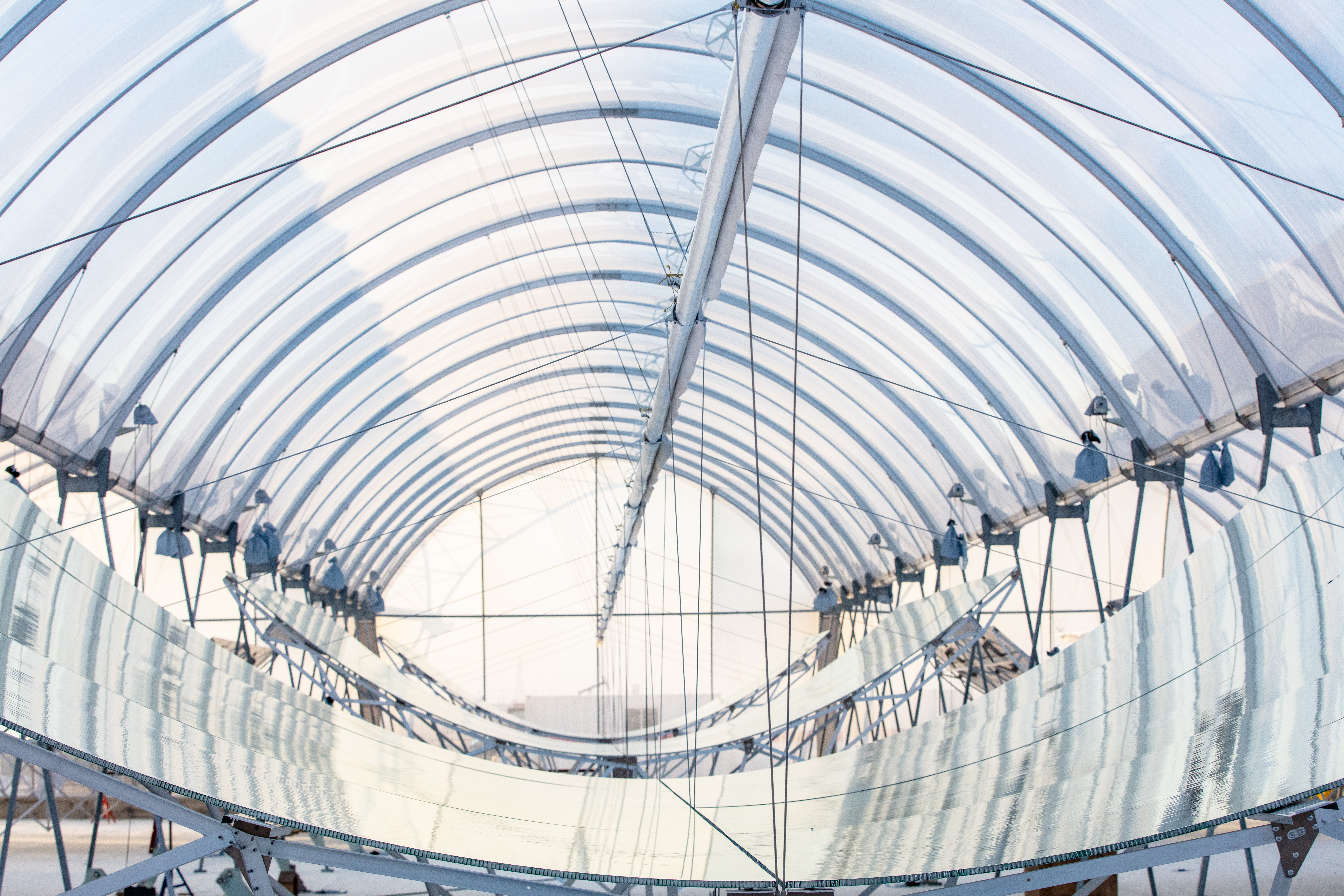 Curved reflective solar troughs sheltered inside a GlassPoint glasshouse