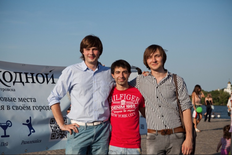 Rodion Yeroshek with friends and early business partners beside a banner for their city-guide project