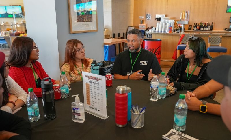 Rodney Rambo speaking with young participants around a table at Camp Flog Gnaw Community Day