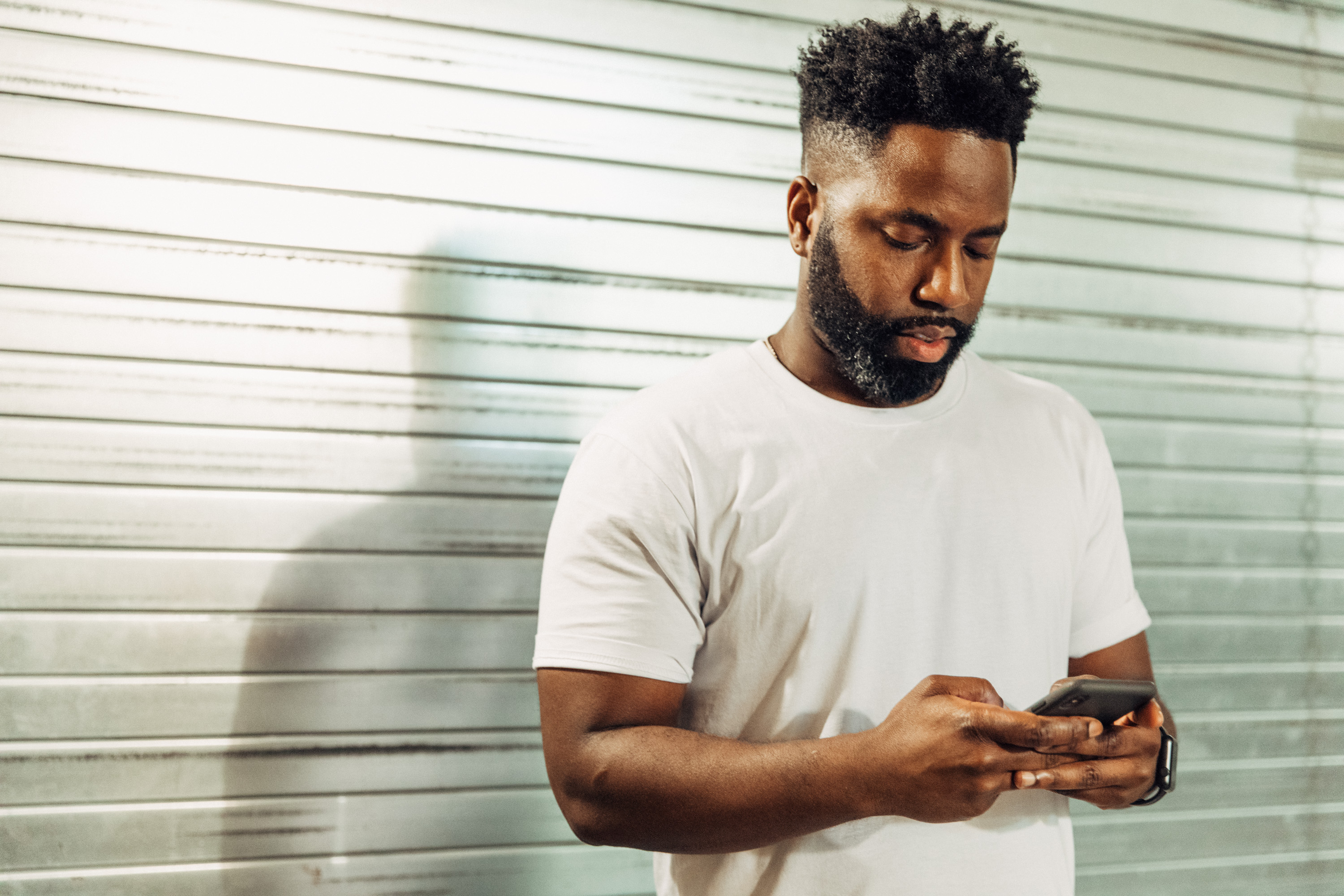 Rodney Williams looking at his phone outside at Black Tech Week Miami in 2018