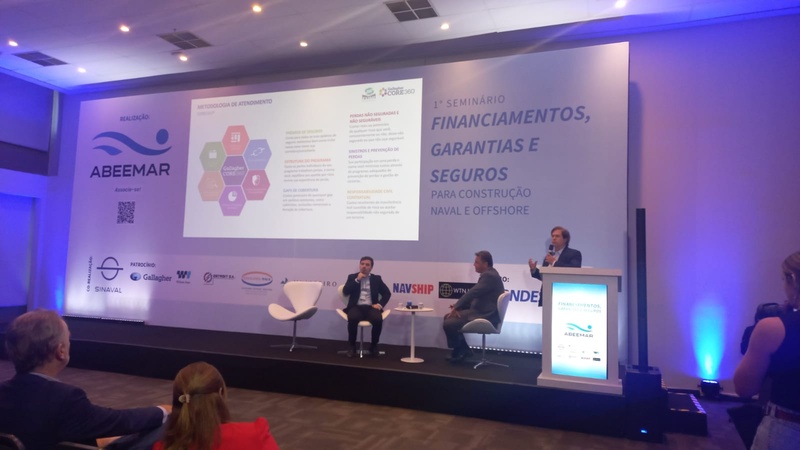 Rodrigo Protasio speaking at a lectern beside fellow panelists at the ABEEMAR naval and offshore seminar in Rio de Janeiro