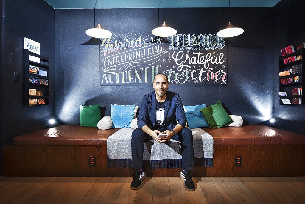 Rodrigo Teijeiro seated on a sofa beneath a wall of entrepreneurial words